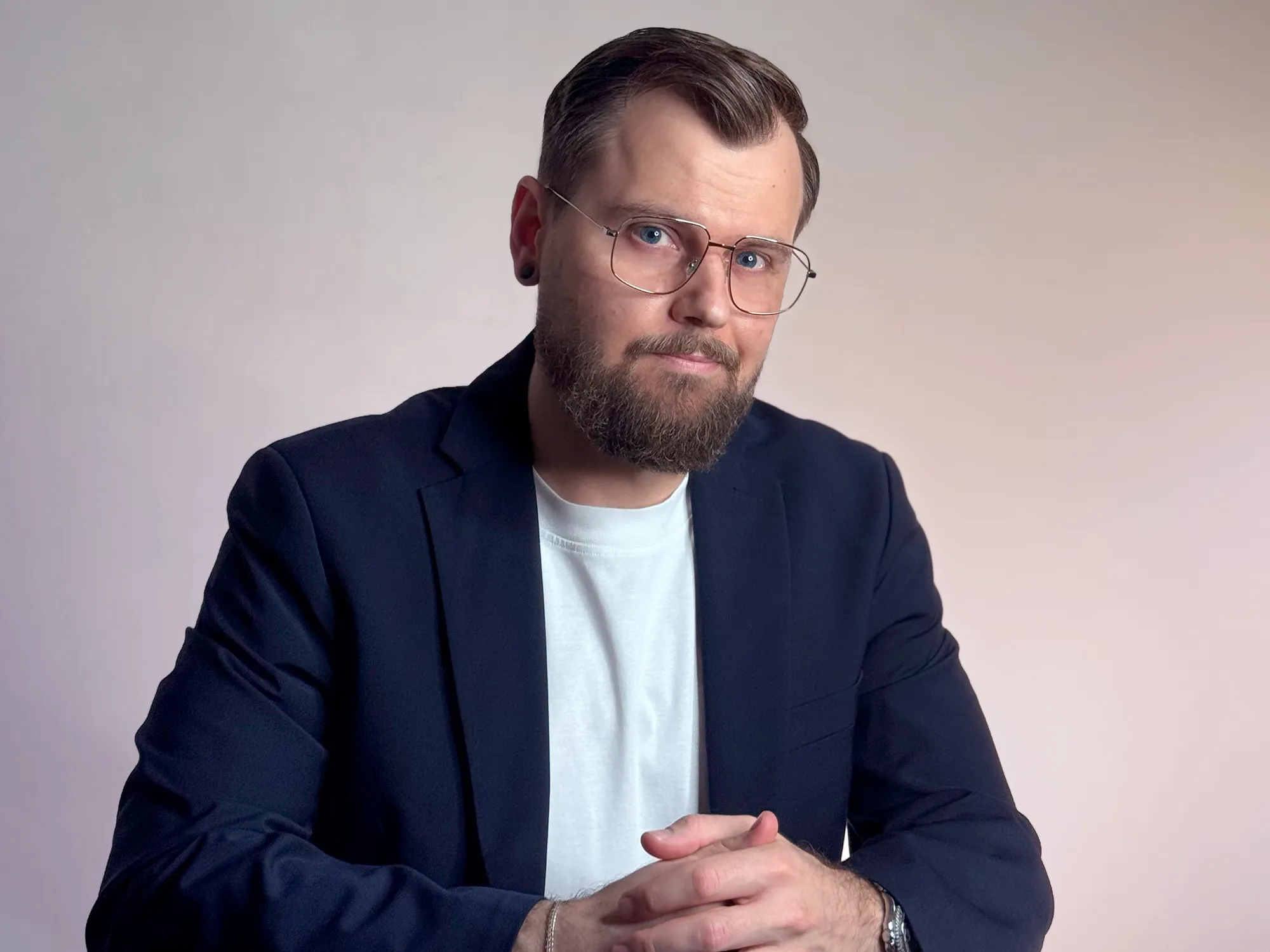 Martin in a black cap and backpack sitting on a rock with snow-covered mountains in the background.